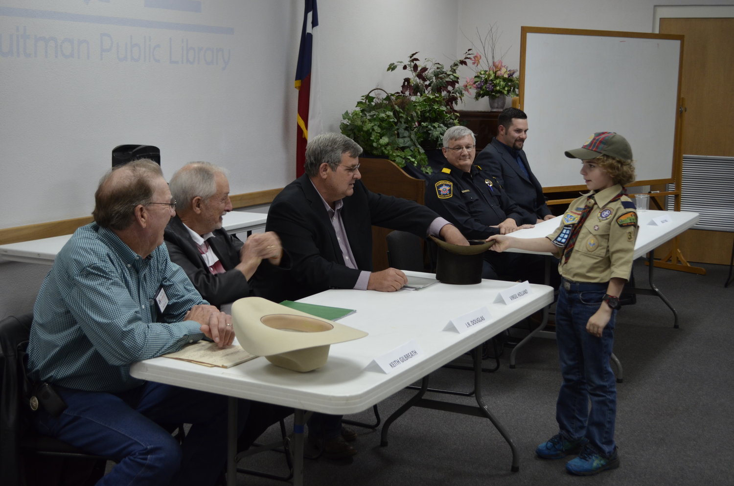 Precinct 1 Commissioner Virgil Holland draws a question from a hat at last Thursday’s candidate forum in Quitman, handled by Quitman Cub Scout Ross Gonyea. Other candidates, from left, include Keith Gilbreath and J.R. Douglas running for commissioner and Steve Bowser and Billy Hill running for constable.